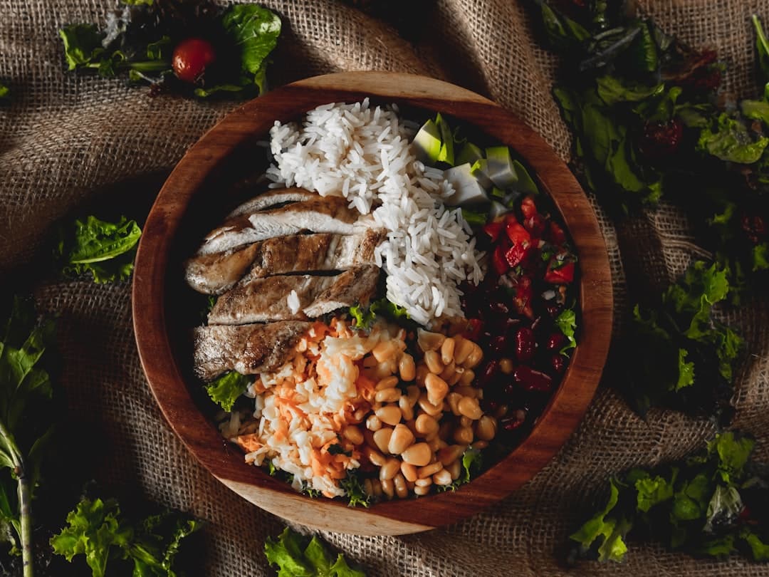 A bowl of grilled chicken, rice, beans and vegetables
